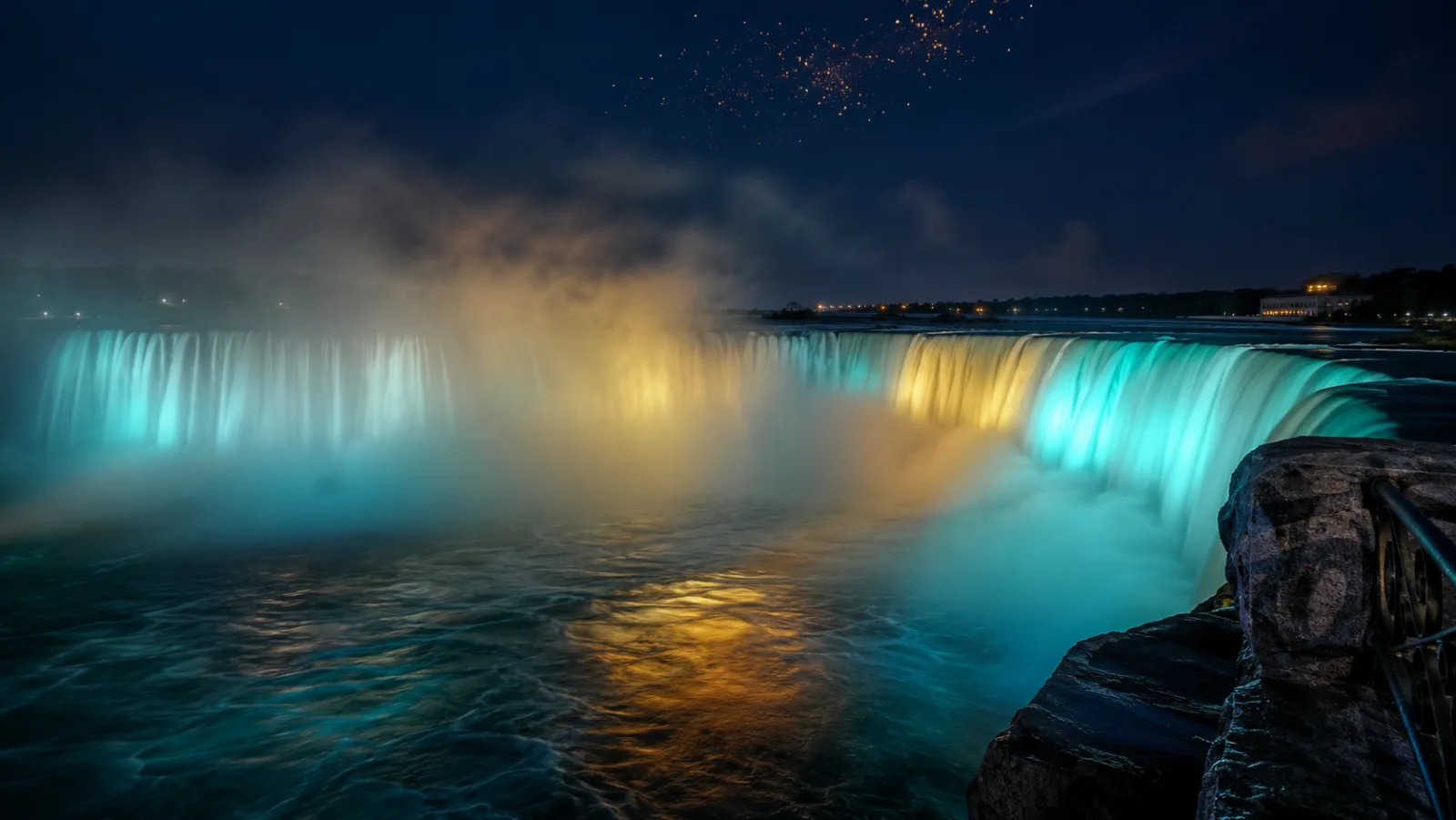 The nightly coloured illumination washing the Canadian Horseshoe Falls in teal and gold light, from the Table Rock promenade edge